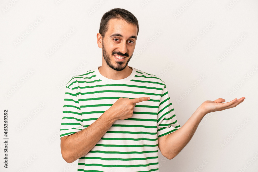 Young caucasian man isolated on white background excited holding a copy space on palm. Young caucasian man isolated on white background excited holding a copy space on palm.