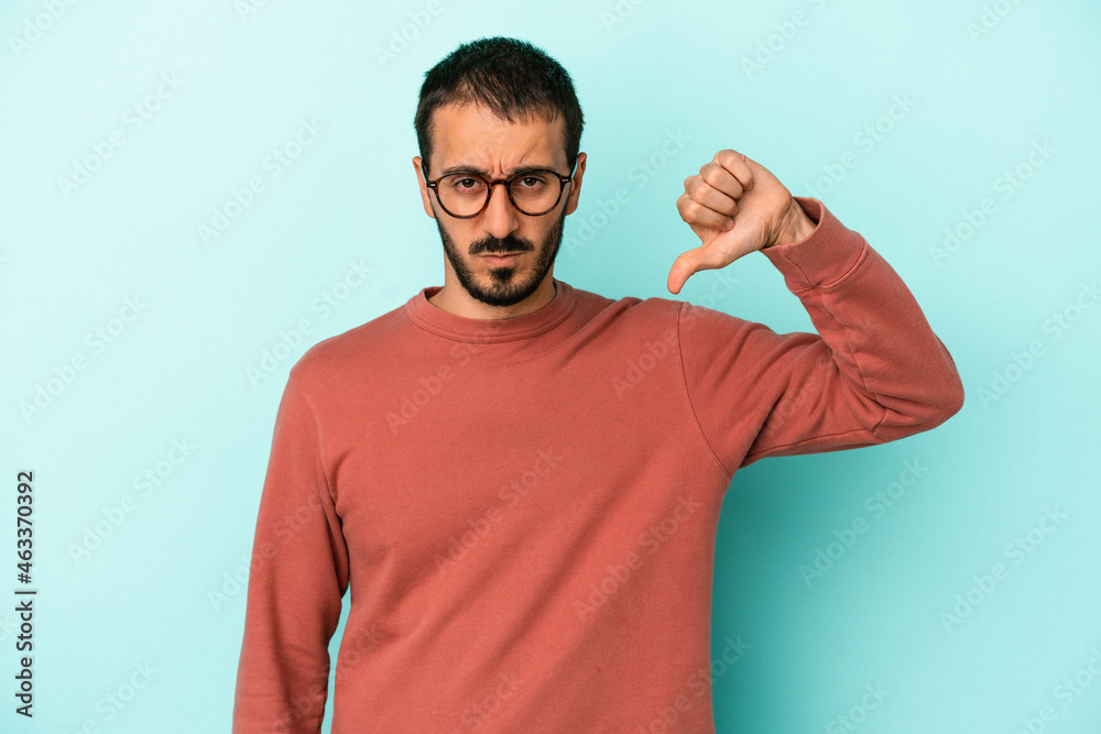 Young caucasian man isolated on blue background showing thumb down, disappointment concept. Young caucasian man isolated on blue background showing thumb down, disappointment concept.
