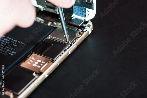 Close-up with the repair of a used smartphone with a screwdriver
