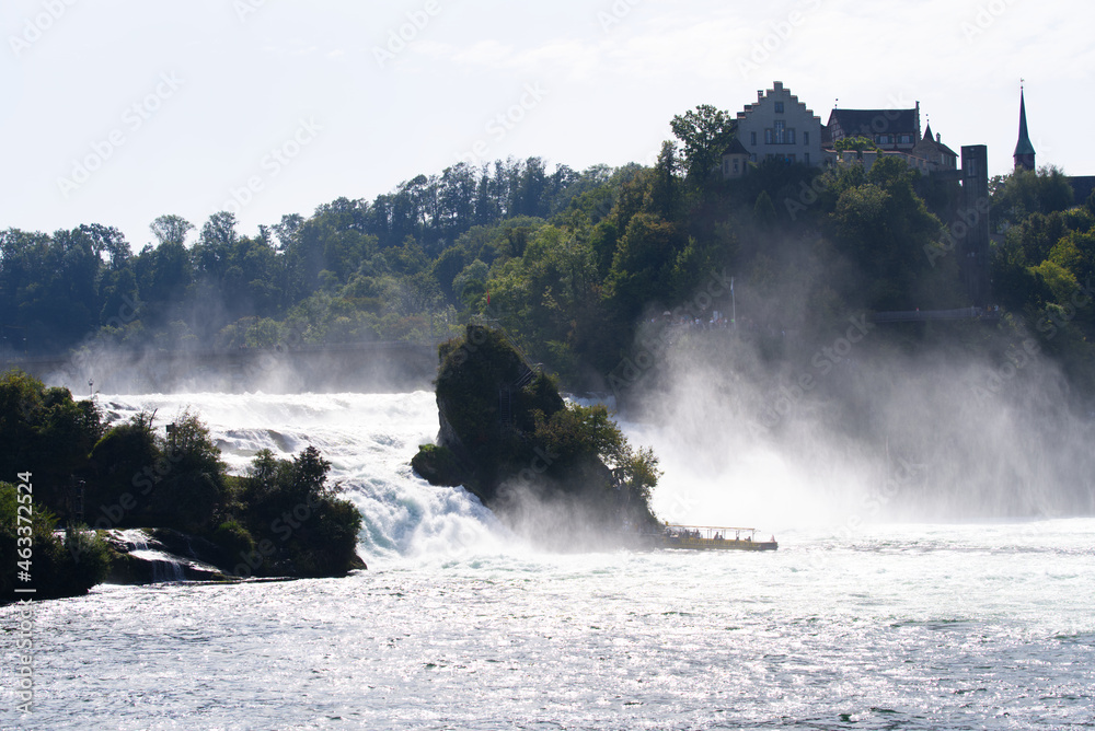 Famous Rhine Falls with rocks, trees and cruise ship on a beautiful autumn day. Photo taken September 25th, 2021, Zürich, Switzerland.