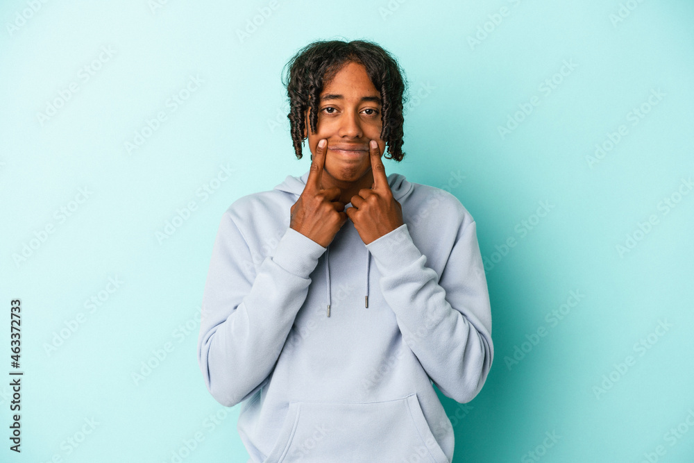 Young african american man isolated on blue background doubting between two options. Young african american man isolated on blue background doubting between two options.