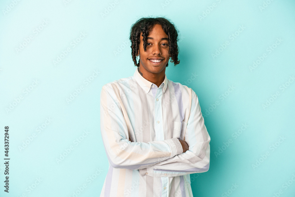 Obraz premium Young african american man isolated on blue background who feels confident, crossing arms with determination.