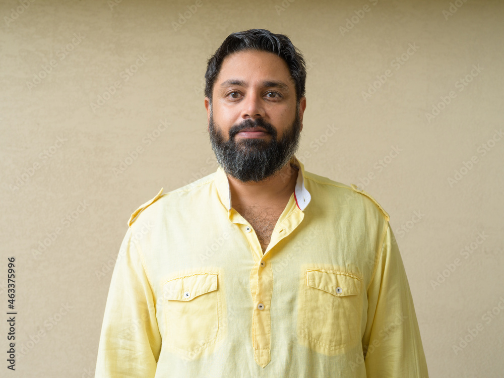 Portrait plus size handsome bearded Indian man against plain background