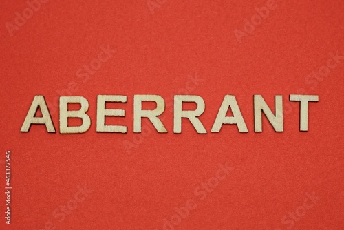 text the word aberrant from gray wooden small letters on an red table