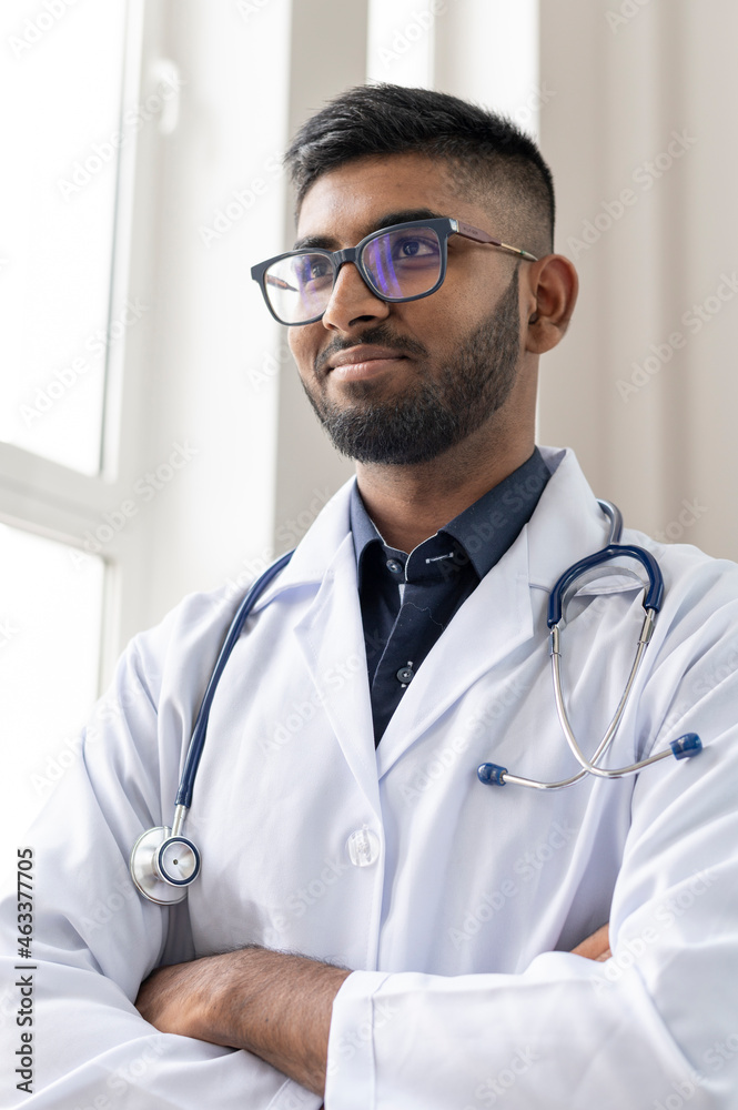 Happy young indian medical student wears glasses and a stethoscope, in a white coat. Portrait in a hospital Happy young indian medical student wears glasses and a stethoscope, in a white coat. Portrait in a hospital