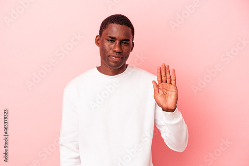 Young African American man isolated on pink background smiling cheerful showing number five with fingers.