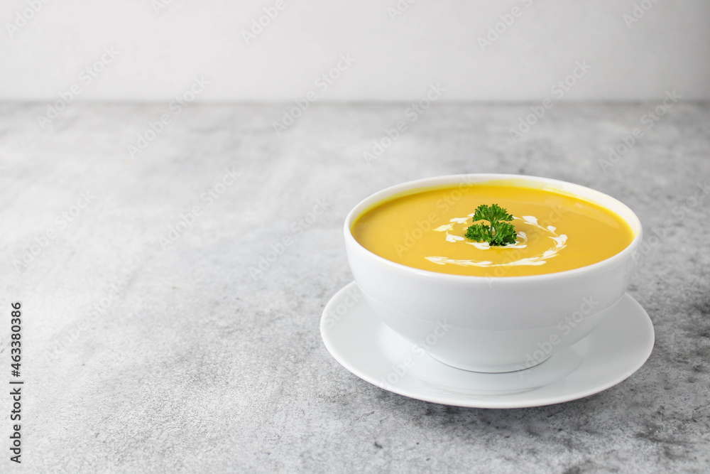 Pumpkin and carrot soup with cream, parsley and seeds on a gray background, copy space Pumpkin and carrot soup with cream, parsley and seeds on a gray background, copy space