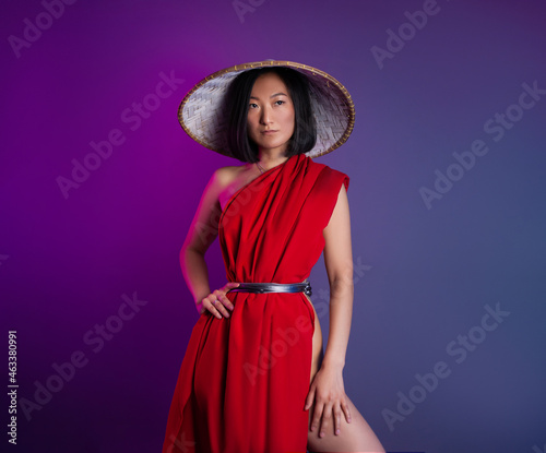 asian woman in red cape and asian hat posing on bright neon background