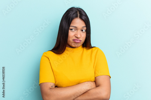 Young Venezuelan woman isolated on blue background tired of a repetitive task.