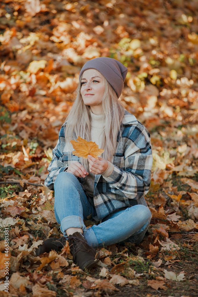 a blonde girl in a plaid shirt in the autumn forest