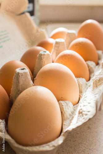 Chicken eggs in cardboard box. Fresh yellow eggs in sunlight. Healthy organic food. Raw brown eggs in container. Farm product concept. Domestic eggs in a row. Breakfast concept. Easter background.