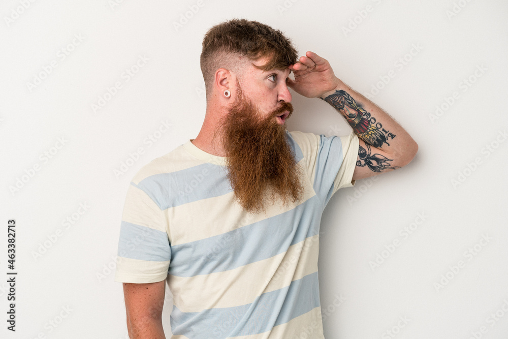 Young caucasian ginger man with long beard isolated on white background looking far away keeping hand on forehead. Young caucasian ginger man with long beard isolated on white background looking far away keeping hand on forehead.