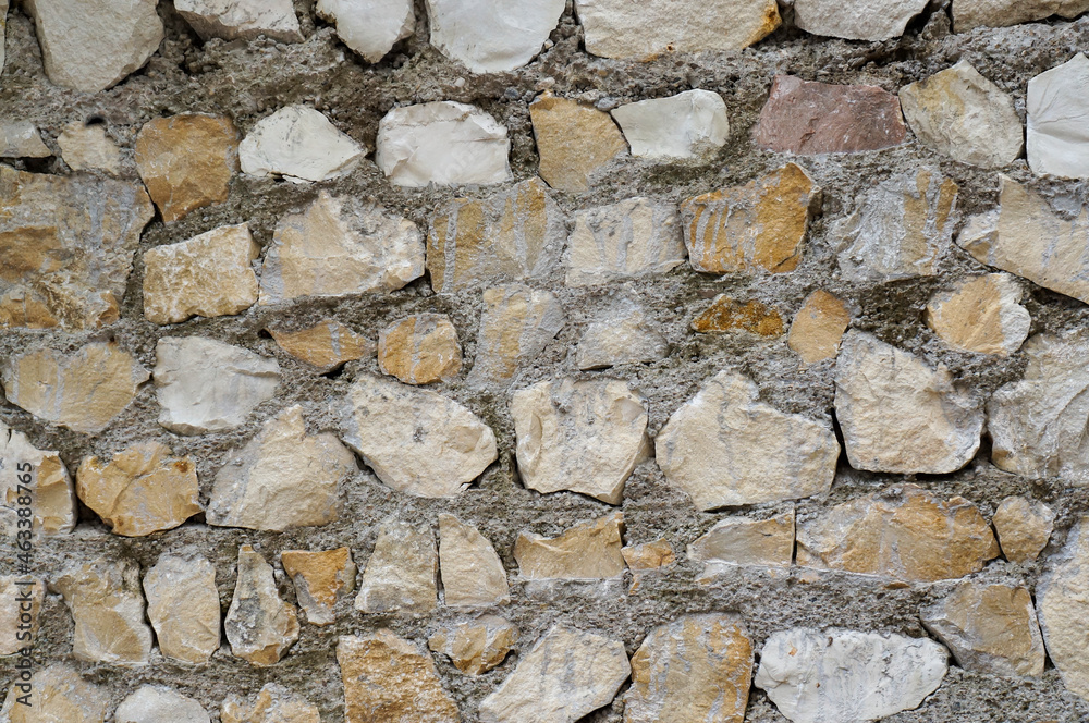 Full frame image of multicolored grunge stone wall. Uneven pieces of marble and sandstone bonded with cement. Closeup stonewall texture for wallpaper or background