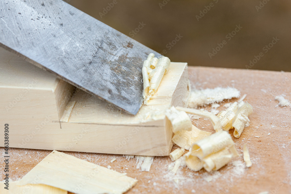 Handmade wooden furniture. A chisel removes shavings from a board, close-up.