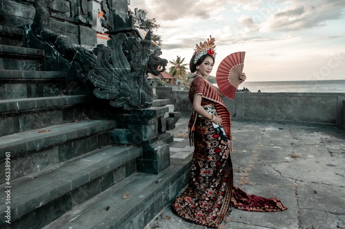 Balinese woman in traditional costume and hand fan, indonesian girl, hindu temple background, Bali.