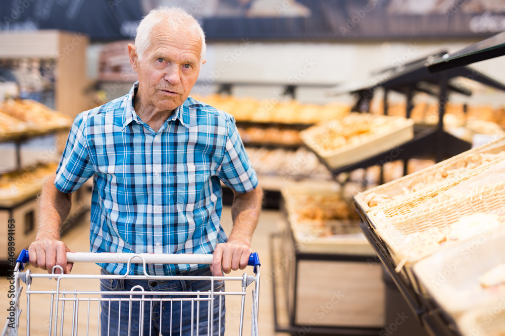 elderly man buying bread and pastries in grocery section of the supermarket