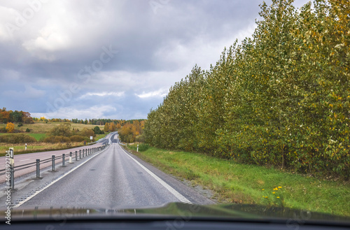 Beautiful view from  front window of a car on highway on an autumn day. Sweden. © Alex