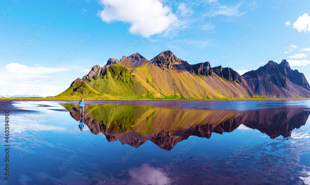 silhouette of a man looking at beautiful landscape with most breathtaking mountains Vestrahorn on the Stokksnes peninsula in the mirror of the lake. (Meditation, antistress - concept).