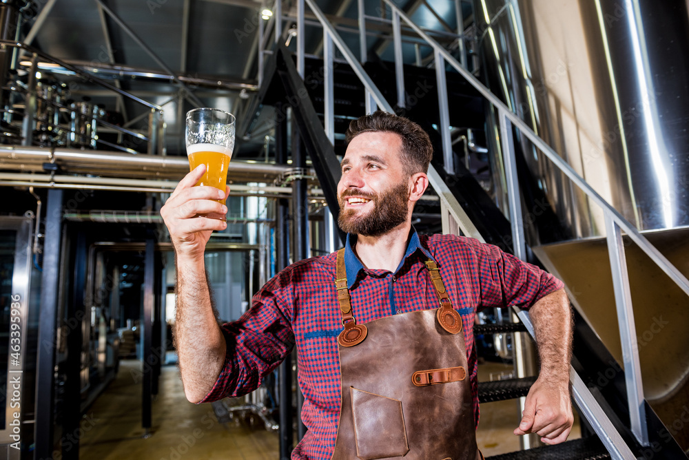 Young male brewer in leather apron at modern brewery factory Young male brewer in leather apron at modern brewery factory