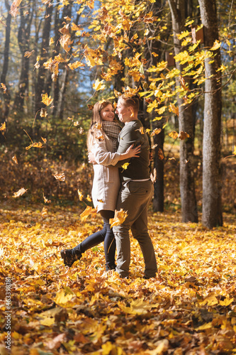 Leisure, relationship concept. Lovely couple enjoy autumn in falling maple tree leaves foreground during sunny day. Bright vivid backlight filter. Faces is in camera focus. Image with motion blur