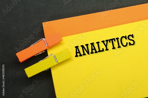 orange and yellow papers are clamped with the word analytics