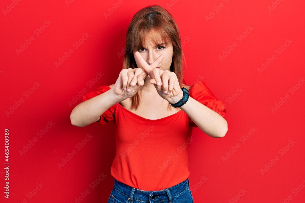 Redhead young woman wearing casual red t shirt rejection expression crossing fingers doing negative sign Redhead young woman wearing casual red t shirt rejection expression crossing fingers doing negative sign