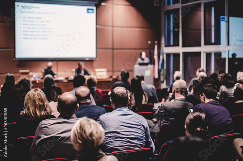 Audience in lecture hall participating at business event.