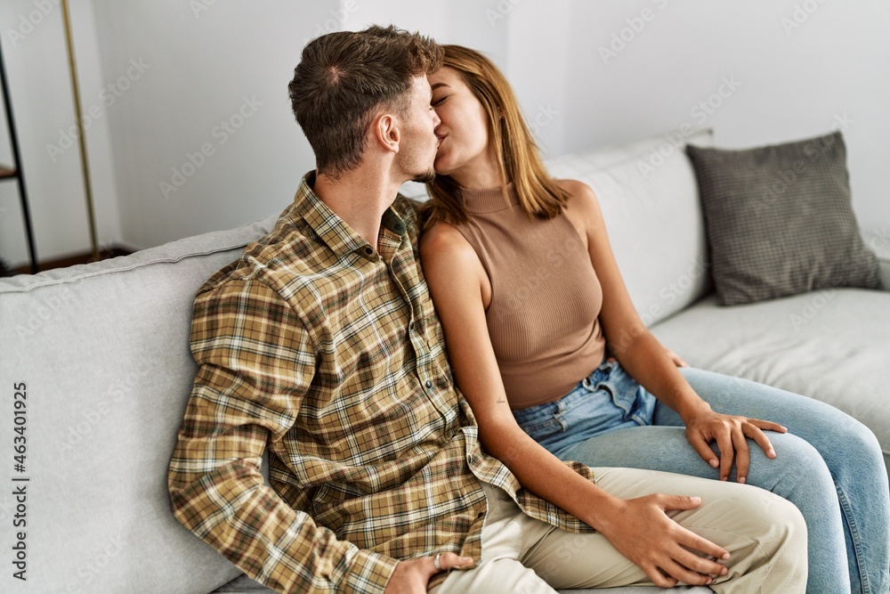 Young hispanic couple kissing and hugging sitting on the sofa at home. Young hispanic couple kissing and hugging sitting on the sofa at home.