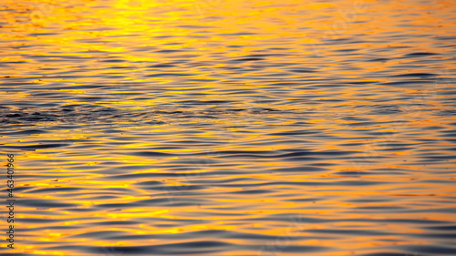Reflection of the setting sun in a wave of water. Natural background texture