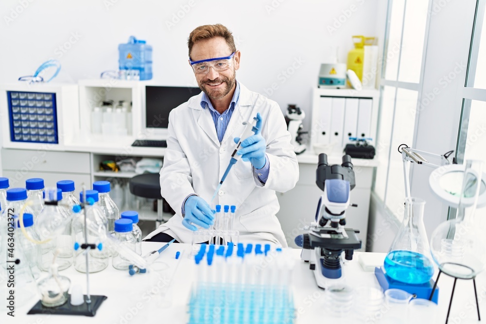 Middle age hispanic man wearing scientist uniform working at laboratory Middle age hispanic man wearing scientist uniform working at laboratory