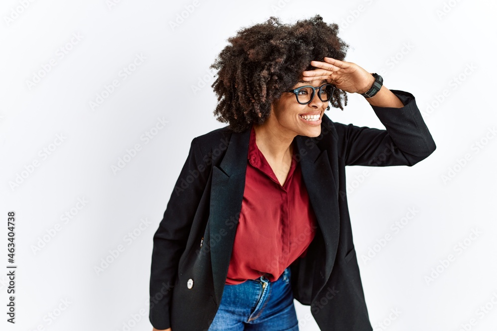 African american woman with afro hair wearing business jacket and glasses very happy and smiling looking far away with hand over head. searching concept. African american woman with afro hair wearing business jacket and glasses very happy and smiling looking far away with hand over head. searching concept.