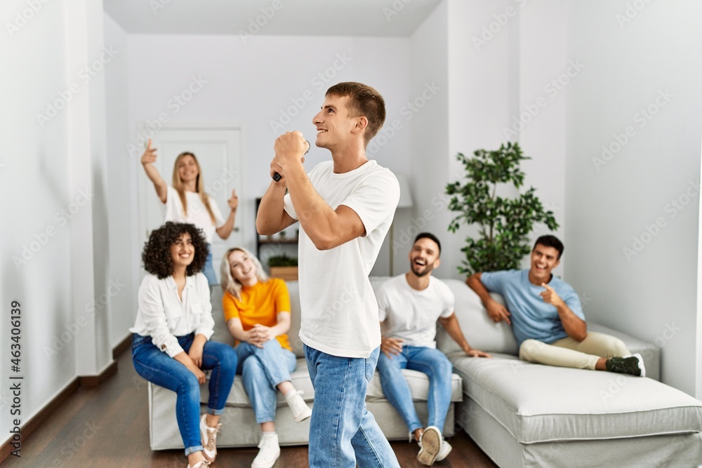 Group of young friends having party singing song using microphone at home. Group of young friends having party singing song using microphone at home.