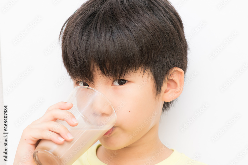 Young little boy drinking chocolate milk isolated in white background. Young little boy drinking chocolate milk isolated in white background.