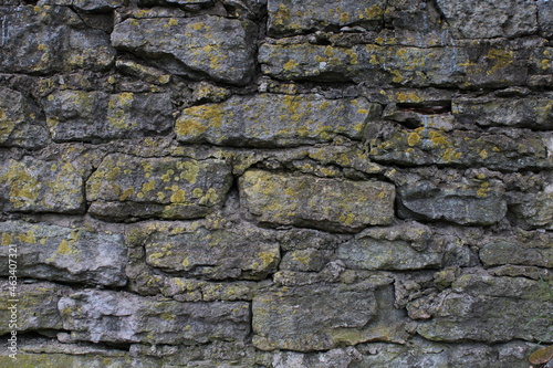 Old gray stone wall, covered by moss