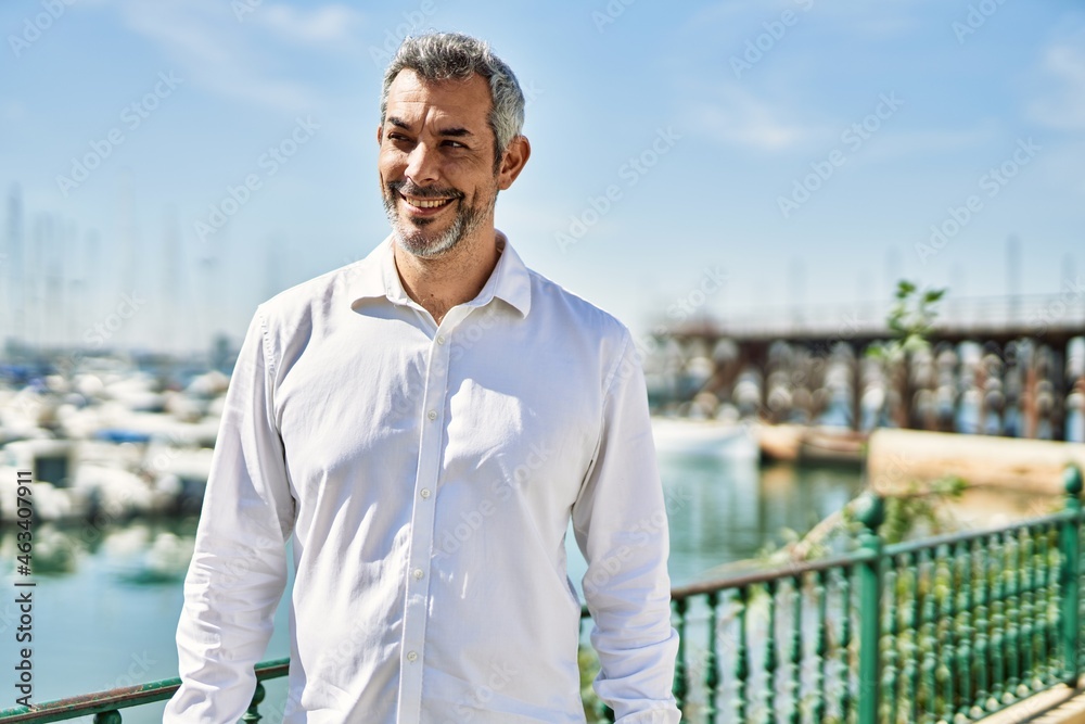 Middle age grey-haired man smiling happy standing at the city.