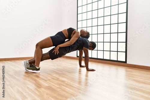 Young african american sporty couple doing push-ups exercise at sport center.