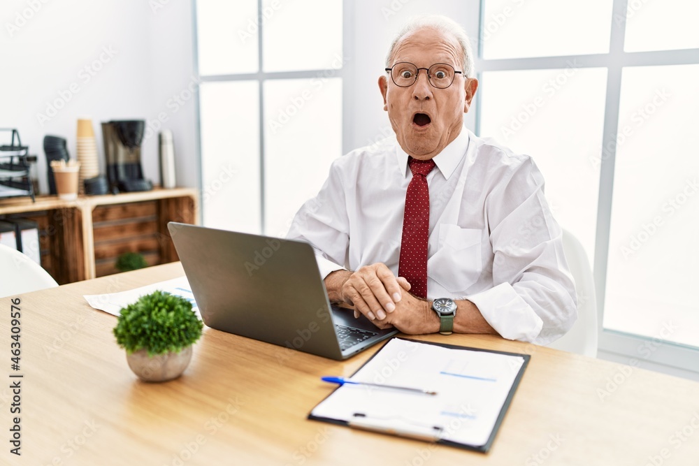 Senior man working at the office using computer laptop afraid and shocked with surprise and amazed expression, fear and excited face. Senior man working at the office using computer laptop afraid and shocked with surprise and amazed expression, fear and excited face.
