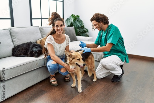 Man and woman wearing veterinarian uniform injecting vaccine to dog at home © Krakenimages.com