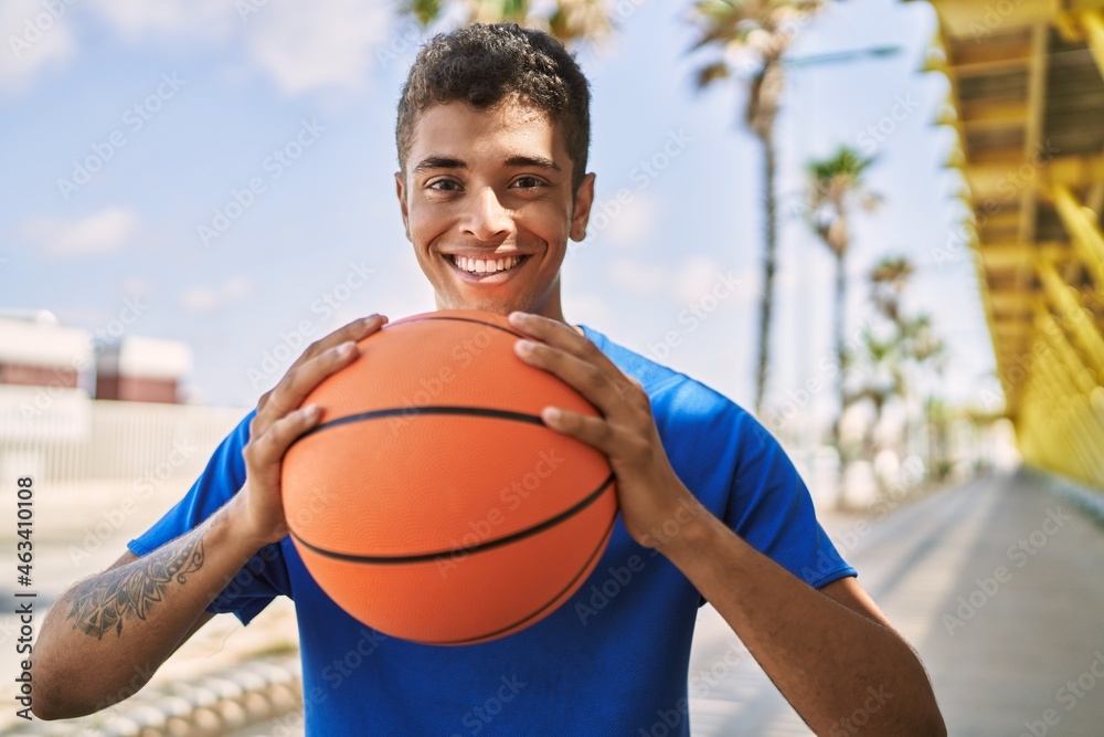 Young hispanic man training with basketball ball outdoors
