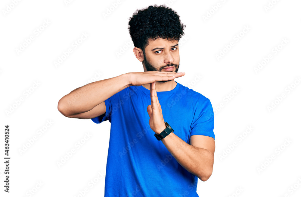 Young arab man with beard wearing casual blue t shirt doing time out gesture with hands, frustrated and serious face Young arab man with beard wearing casual blue t shirt doing time out gesture with hands, frustrated and serious face