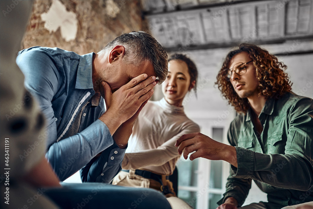 Young despair man crying during group therapy. Young despair man crying during group therapy.