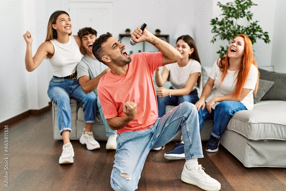 Group of young friends having party singing song using microphone at home. Group of young friends having party singing song using microphone at home.