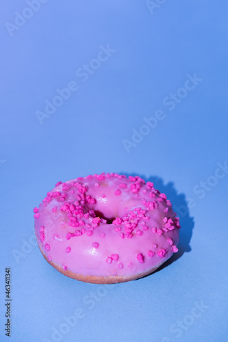 Pink glazed sugar donut with trendy blue pop background