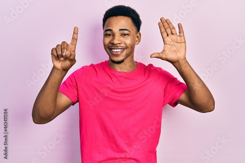 Young african american man wearing casua t shirt showing and pointing up with fingers number six while smiling confident and happy.