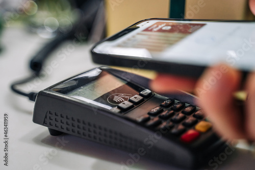 Payment for goods through a bank terminal in a contactless way using a smartphone (apple pay). Flower show in the store.