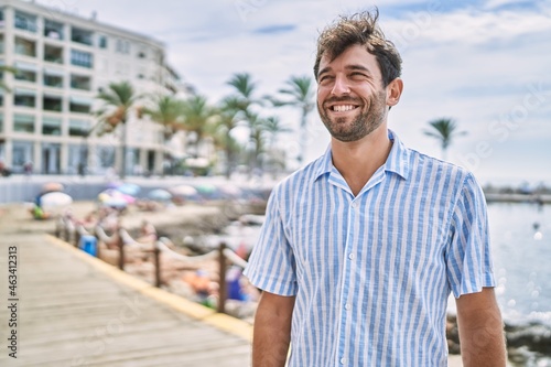 Young hispanic man smiling happy standing at the beach.