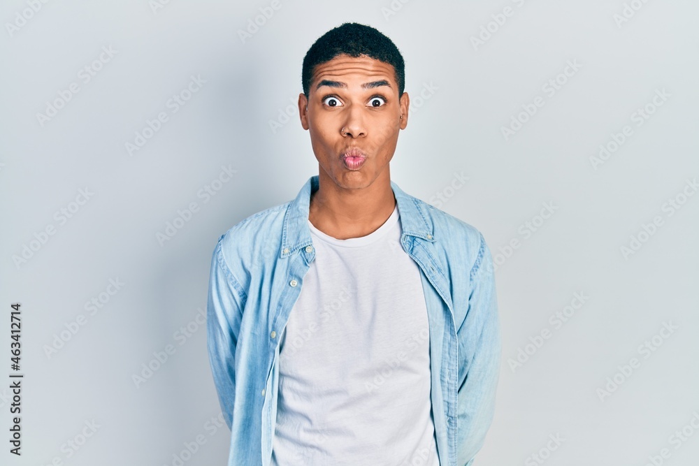 Young african american guy wearing casual clothes making fish face with lips, crazy and comical gesture. funny expression. Young african american guy wearing casual clothes making fish face with lips, crazy and comical gesture. funny expression.