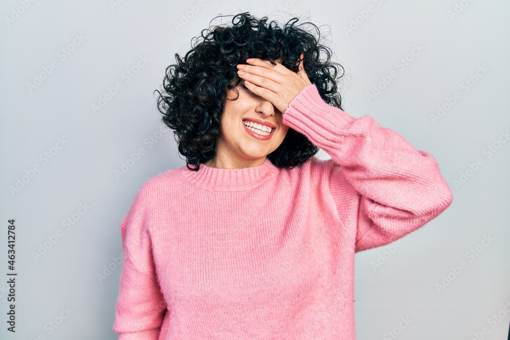 Young middle east woman wearing casual clothes smiling and laughing with hand on face covering eyes for surprise. blind concept. Young middle east woman wearing casual clothes smiling and laughing with hand on face covering eyes for surprise. blind concept.