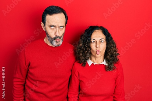 Middle age couple of hispanic woman and man hugging and standing together making fish face with lips, crazy and comical gesture. funny expression. © Krakenimages.com