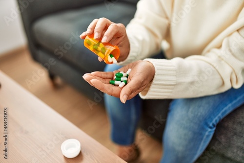 Middle age hispanic woman taking pills at home